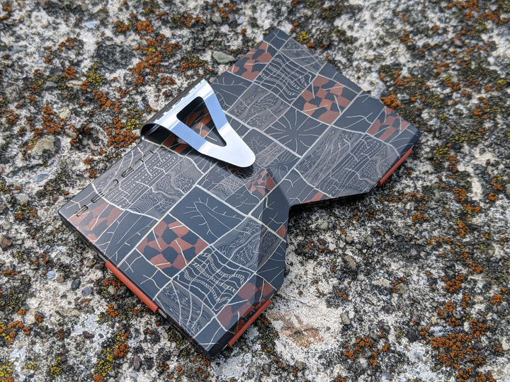 THE ARTIFICER wallet with the money clip attachment installed, sitting on a moss and lichen covered rock.